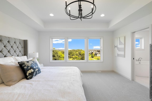 carpeted bedroom featuring a notable chandelier, a raised ceiling, and connected bathroom