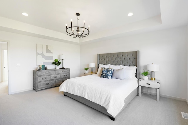 carpeted bedroom with an inviting chandelier and a tray ceiling