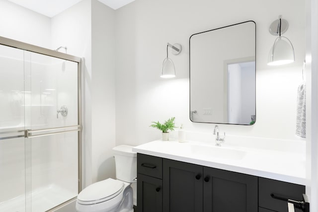 bathroom featuring vanity, a shower with shower door, and toilet