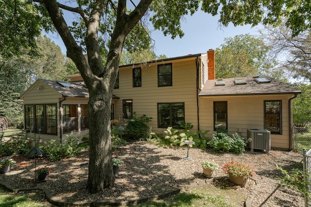 rear view of property featuring a sunroom and central AC