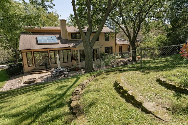 rear view of property with a sunroom, a yard, and a patio area