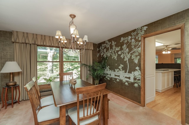 dining space with ceiling fan with notable chandelier, light hardwood / wood-style flooring, and a baseboard heating unit