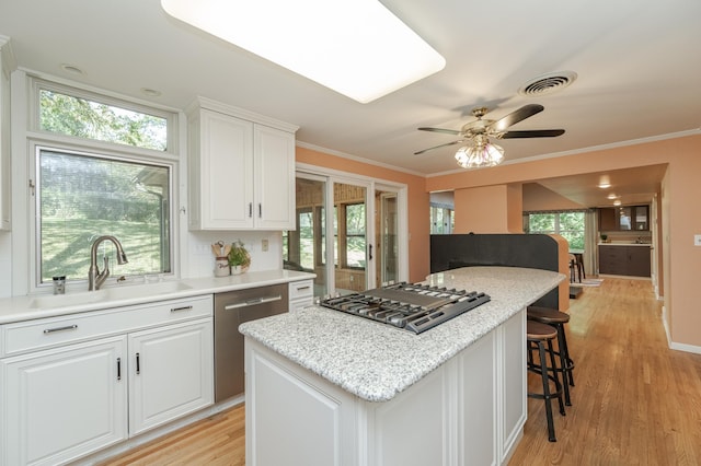 kitchen with appliances with stainless steel finishes, plenty of natural light, light wood-type flooring, and white cabinets