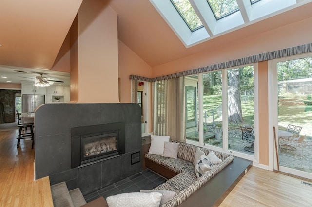 interior space with a fireplace, lofted ceiling with skylight, and ceiling fan