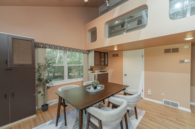 dining area featuring light hardwood / wood-style flooring and high vaulted ceiling