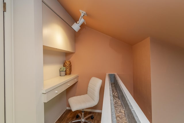 office area with lofted ceiling, built in desk, and hardwood / wood-style flooring