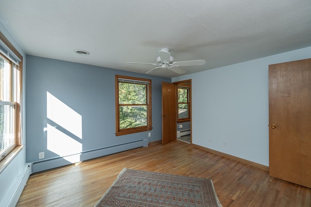 spare room with a baseboard radiator, a wealth of natural light, ceiling fan, and light wood-type flooring