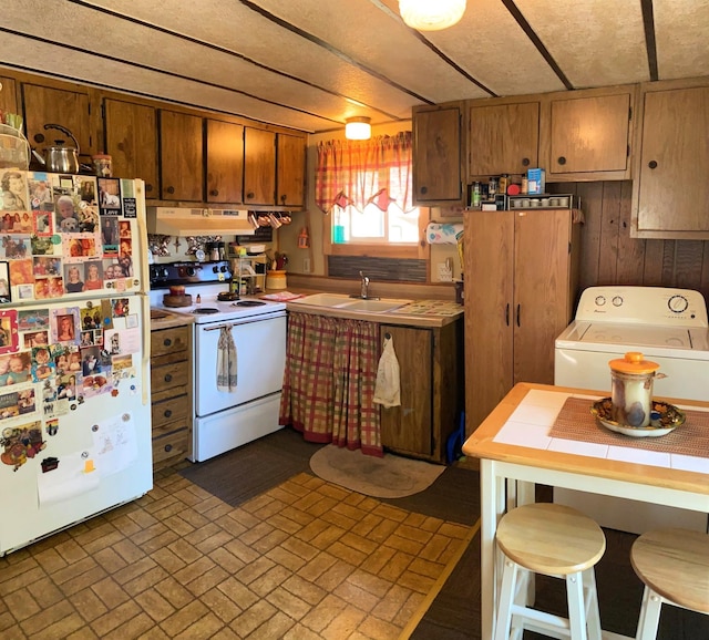 kitchen featuring washer / dryer, white appliances, sink, and wooden walls