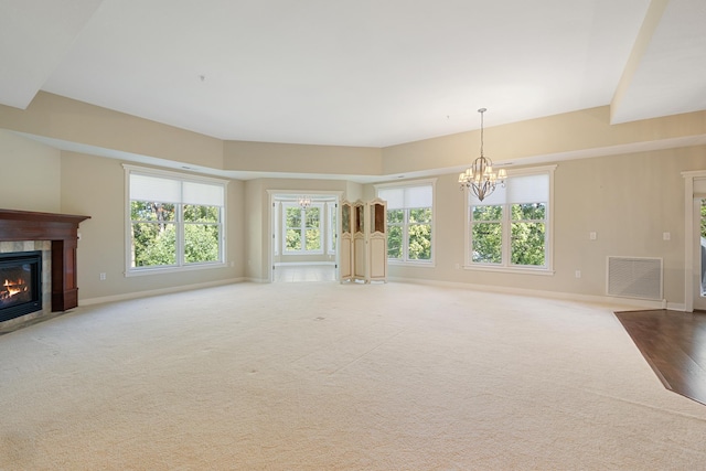 unfurnished living room featuring an inviting chandelier, carpet flooring, and a fireplace