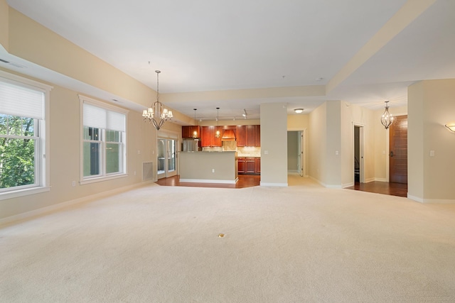 unfurnished living room featuring carpet and an inviting chandelier