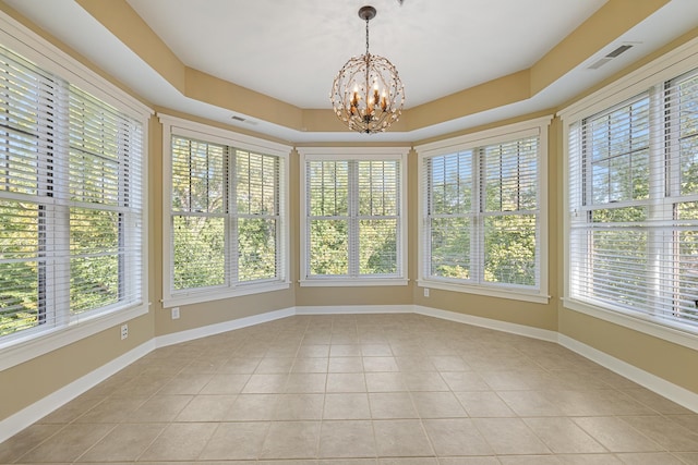 unfurnished sunroom with a notable chandelier, a wealth of natural light, and a raised ceiling