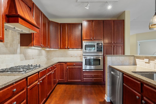 kitchen featuring light stone counters, hanging light fixtures, custom range hood, appliances with stainless steel finishes, and dark hardwood / wood-style flooring