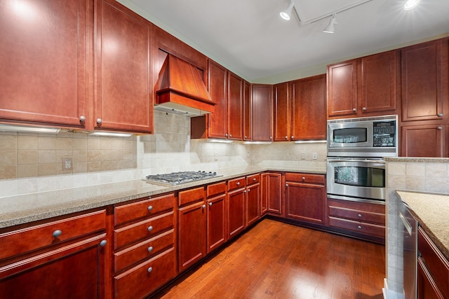 kitchen featuring premium range hood, dark hardwood / wood-style flooring, stainless steel appliances, and light stone countertops