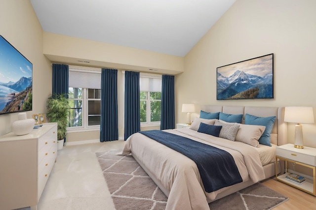 bedroom featuring high vaulted ceiling and light hardwood / wood-style floors