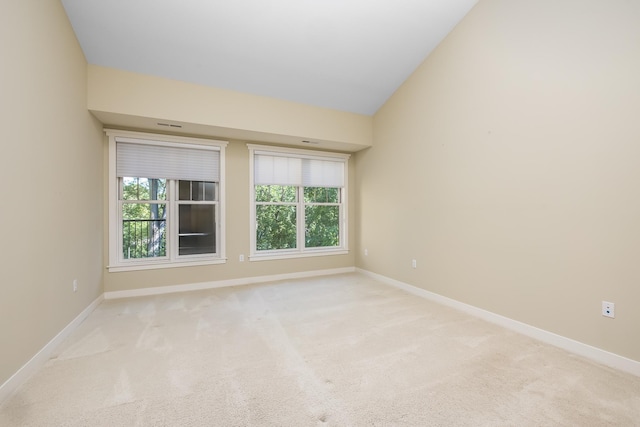 spare room featuring light carpet and lofted ceiling