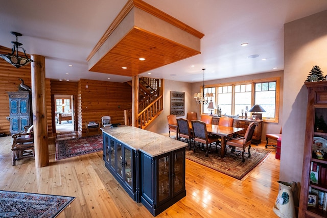 kitchen with blue cabinets, light stone counters, pendant lighting, light wood-type flooring, and an inviting chandelier