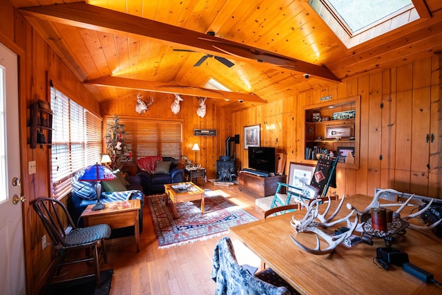 living room featuring hardwood / wood-style flooring, vaulted ceiling with skylight, and wood walls