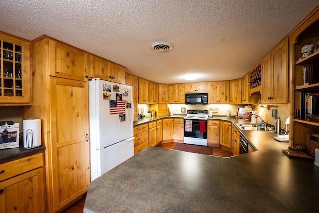 kitchen featuring a textured ceiling, white appliances, sink, and kitchen peninsula