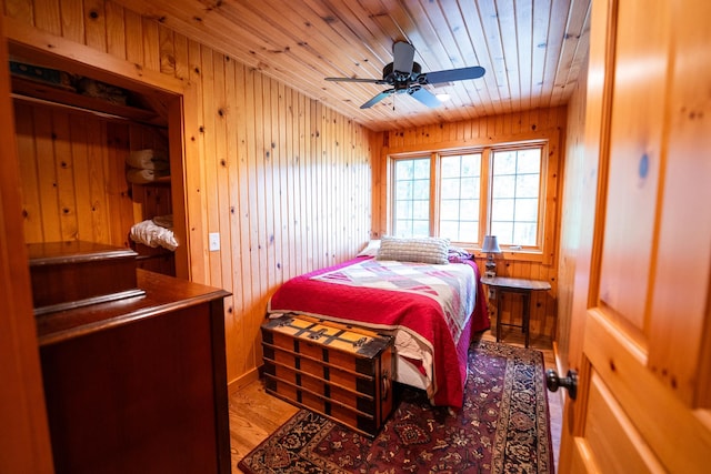 bedroom featuring wooden ceiling, wood walls, ceiling fan, and light hardwood / wood-style flooring