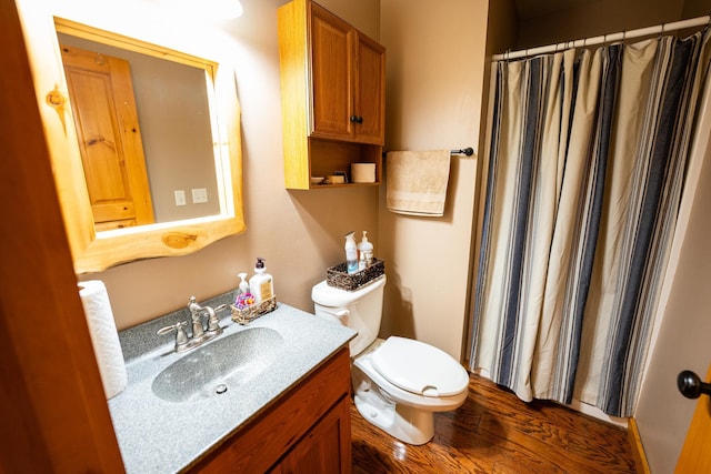 bathroom with wood-type flooring, curtained shower, vanity, and toilet