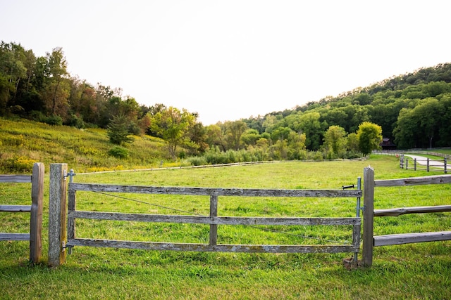 view of gate with a rural view and a lawn