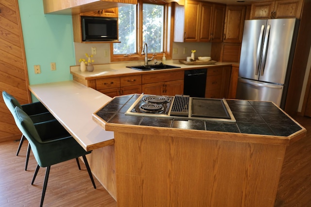 kitchen featuring sink, black appliances, kitchen peninsula, and light wood-type flooring