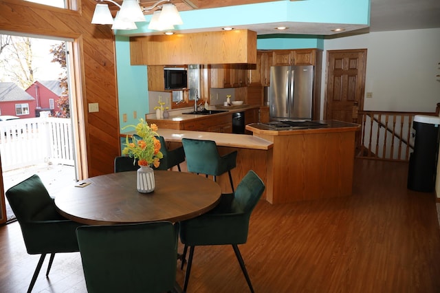 dining space featuring a notable chandelier, wood walls, sink, and hardwood / wood-style floors