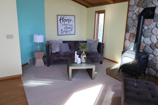 living room with hardwood / wood-style flooring, a wood stove, and vaulted ceiling with beams