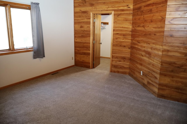 carpeted empty room with wood walls