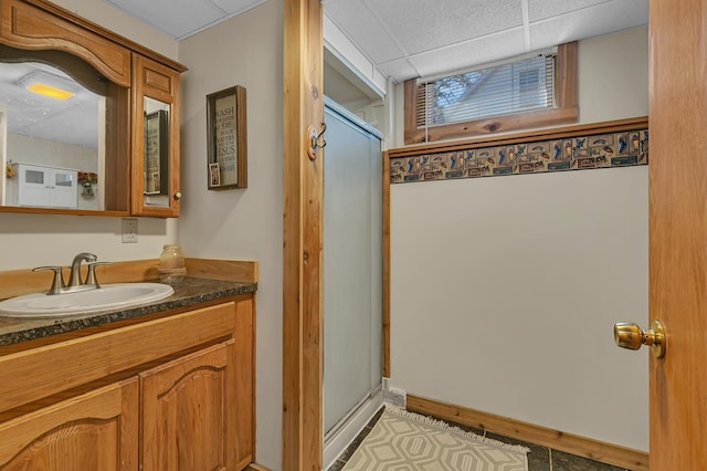 bathroom featuring vanity, an enclosed shower, and a drop ceiling