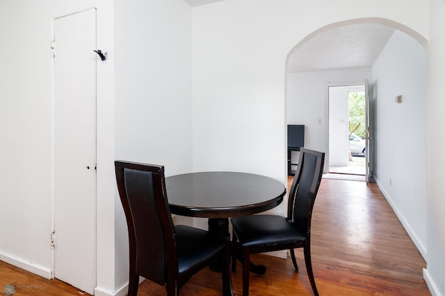 dining area with wood-type flooring and a textured ceiling