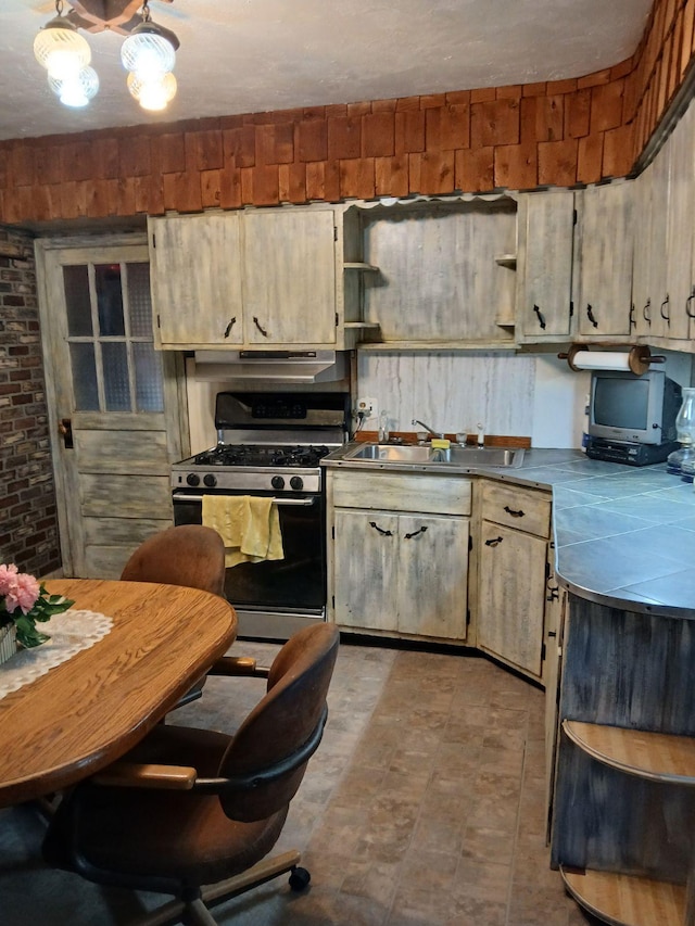 kitchen featuring brick wall, sink, and range with gas cooktop