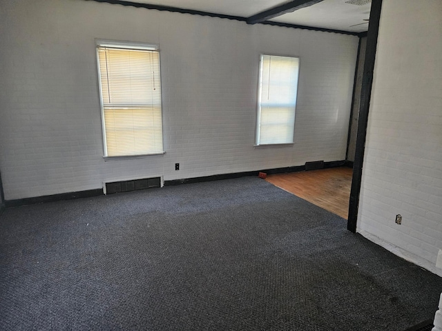 unfurnished room with brick wall and hardwood / wood-style floors