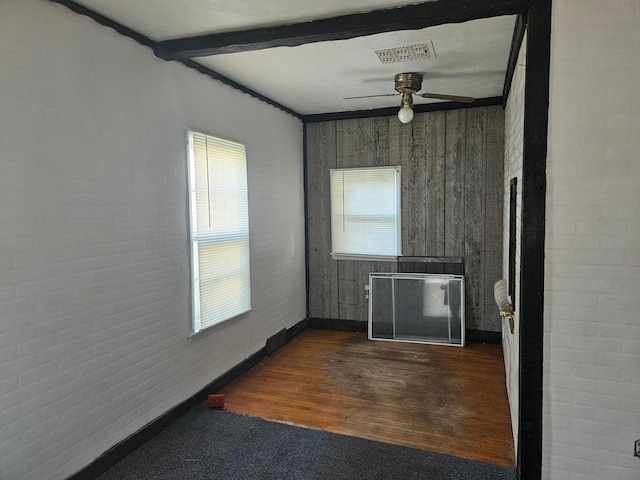 spare room with beam ceiling, ceiling fan, plenty of natural light, and dark hardwood / wood-style flooring