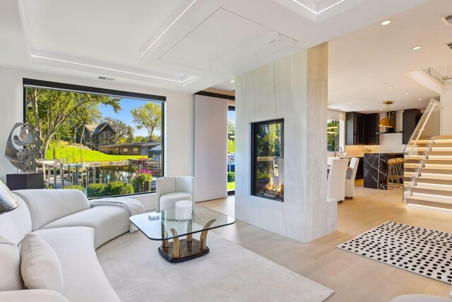 living room featuring a water view, a large fireplace, and light hardwood / wood-style flooring