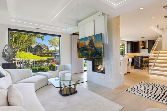 living room featuring a multi sided fireplace and light hardwood / wood-style flooring