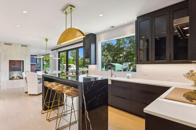 kitchen with a breakfast bar, sink, light hardwood / wood-style flooring, and decorative light fixtures