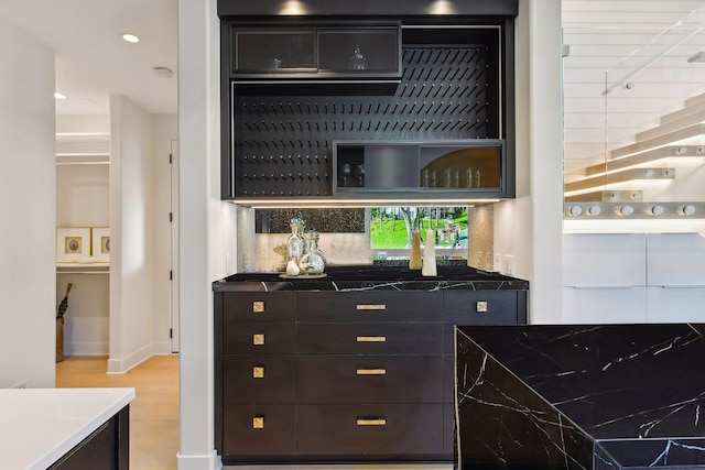 bar featuring light wood-style floors, backsplash, indoor bar, and recessed lighting