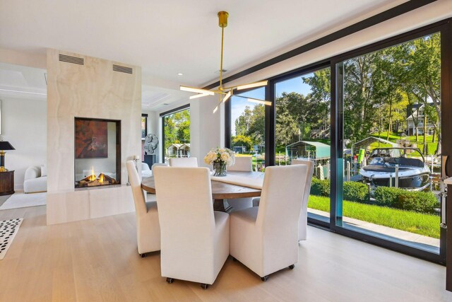 dining space featuring light hardwood / wood-style floors, a high end fireplace, and a wealth of natural light