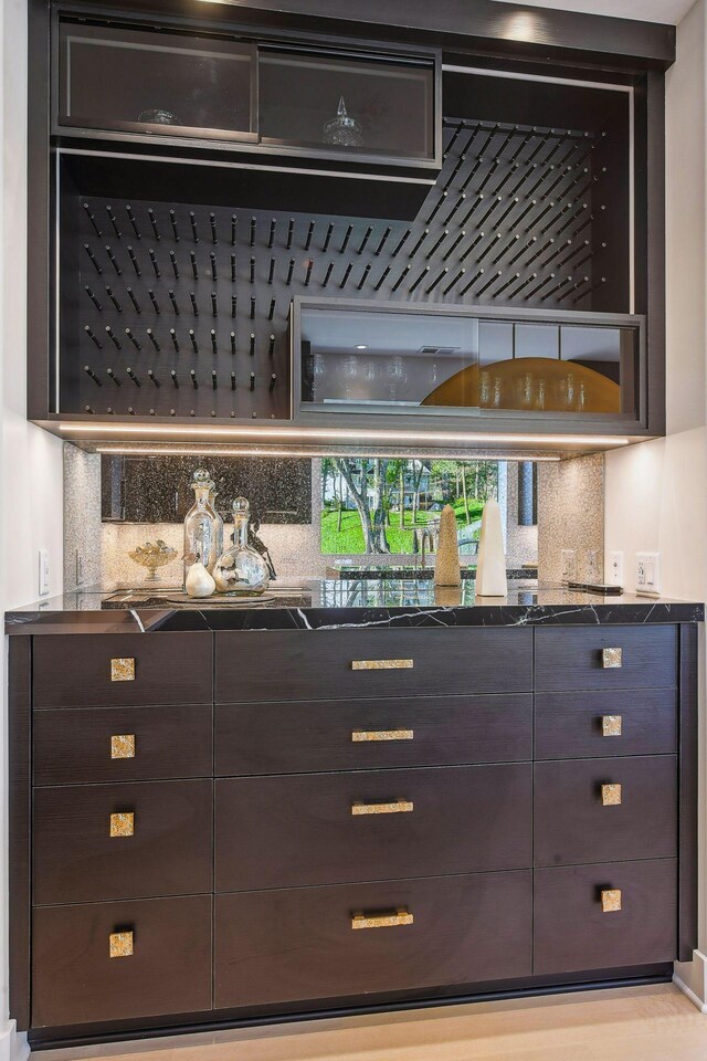 bar with decorative backsplash and dark brown cabinetry