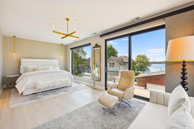 bedroom featuring a water view, baseboards, visible vents, and wood finished floors