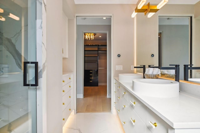 bathroom featuring double vanity, an enclosed shower, wood finished floors, a sink, and a spacious closet