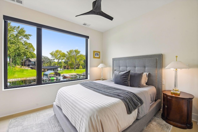 bedroom with baseboards, a ceiling fan, wood finished floors, and visible vents