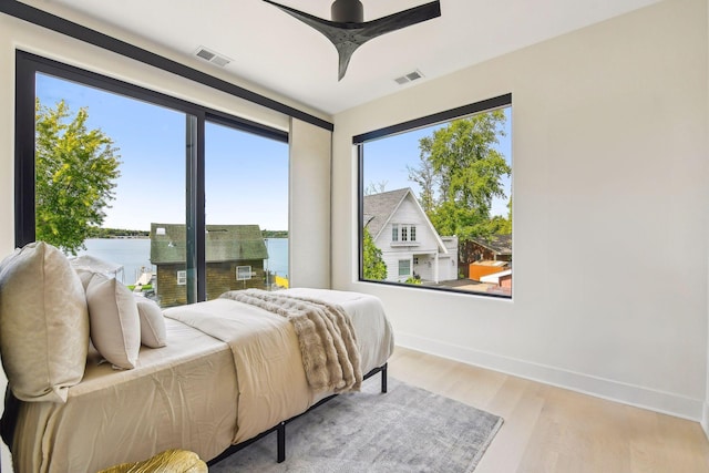 bedroom featuring baseboards, ceiling fan, light wood-type flooring, and visible vents