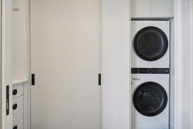 clothes washing area with stacked washer and clothes dryer and laundry area