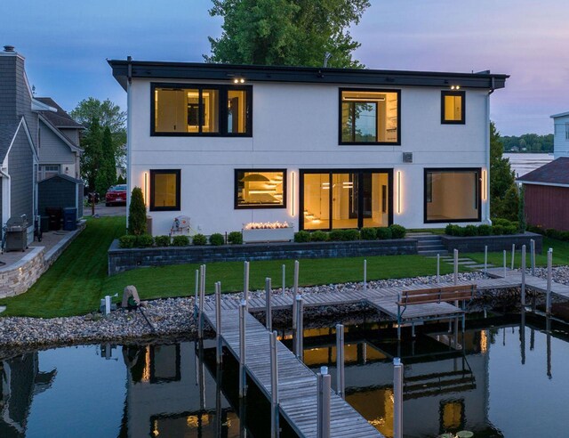 back house at dusk featuring a water view and a yard