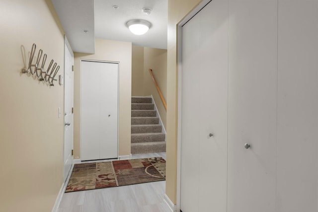 foyer featuring wood finished floors, baseboards, and stairway
