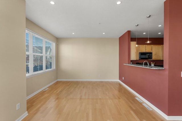 interior space featuring black microwave, light wood finished floors, recessed lighting, and baseboards