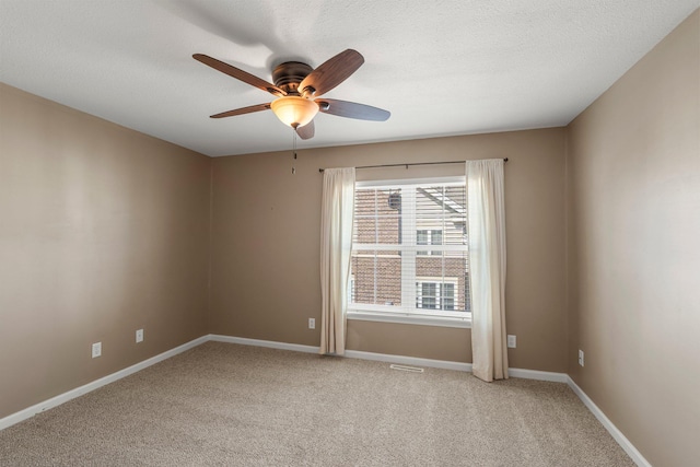 spare room featuring ceiling fan, light carpet, and baseboards