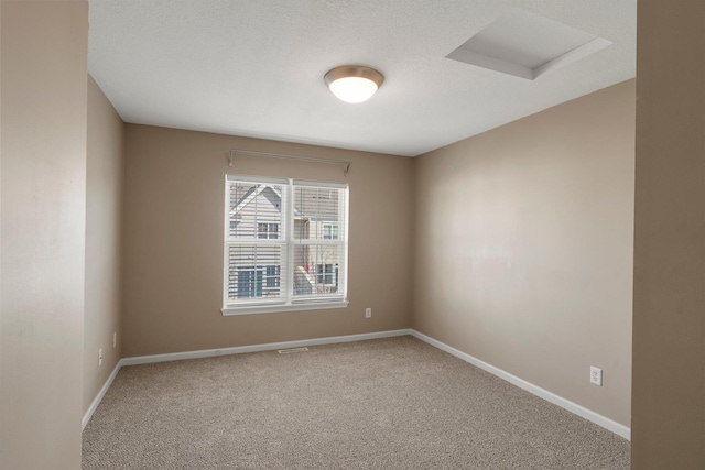 carpeted empty room featuring attic access, visible vents, and baseboards